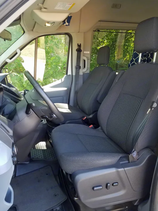 Inside an RV rental: Front cabin featuring comfortable driver and passenger seats, steering wheel, and dashboard view.. Ford transit 2017