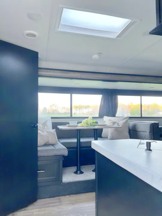 Bright RV rental interior with a dinette, large windows showing nature, and a kitchen counter. Ideal for travel.. Forest River Cherokee Grey Wolf 2021