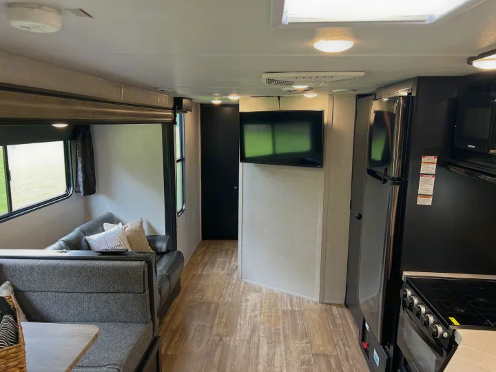 View inside an RV rental showing the living area with sofa, kitchen with fridge/stove, and TV. Ideal for travel.. Forest River Cherokee Grey Wolf 2021