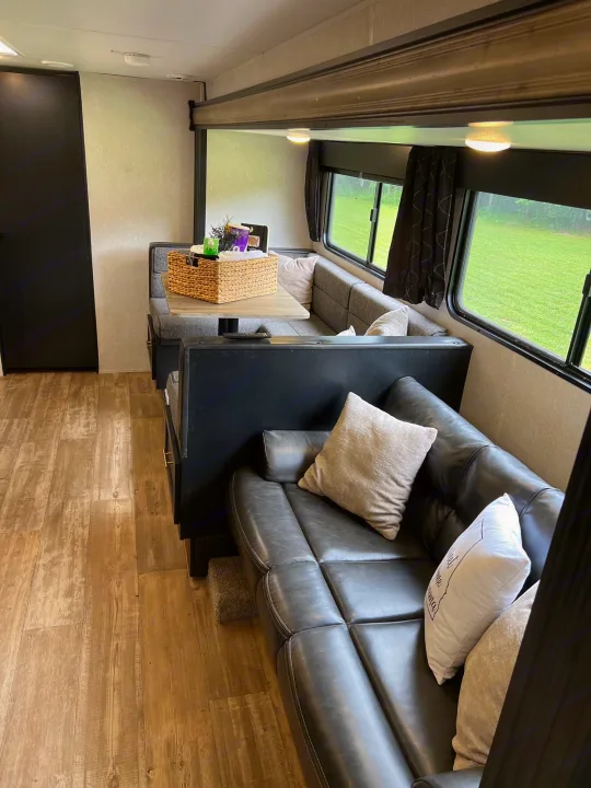 Inside this modern RV rental: a plush sofa, dinette with table, and wood-toned flooring. Enjoy comfortable travel.. Forest River Cherokee Grey Wolf 2021