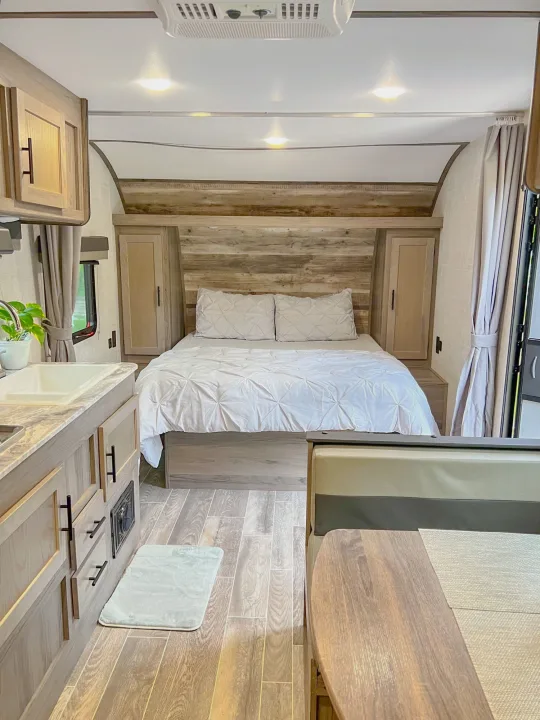 Cozy modern RV rental interior featuring a comfortable bed, kitchenette, and dinette area, ideal for travel adventures.. Gulf Stream Ameri-Lite 2022