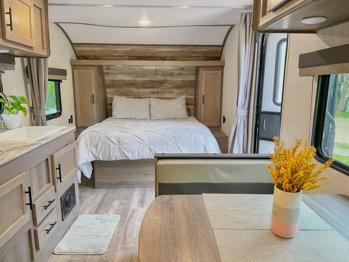 Cozy RV rental interior showcasing a full bed, kitchen sink, and dining booth. Perfect for travel!. Gulf Stream Ameri-Lite 2022