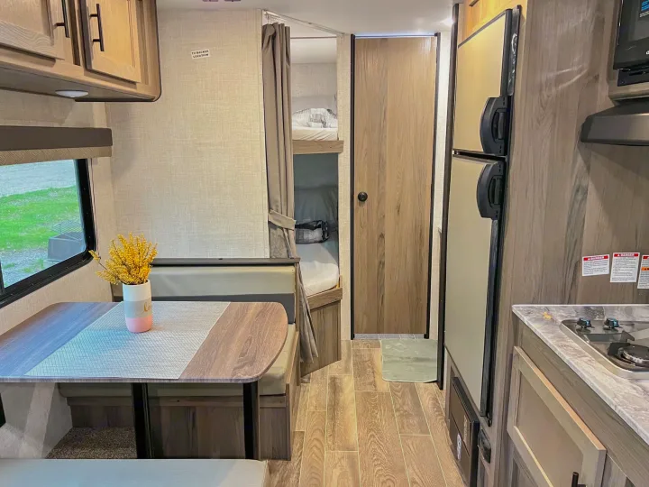 This RV rental interior showcases a kitchen, dining area, and bunk beds, a functional living space for travel.. Gulf Stream Ameri-Lite 2022