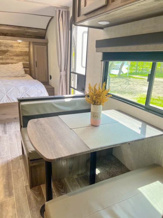 Experience comfortable rv rental living with this modern interior, featuring a cozy bed and dinette with scenic views.. Gulf Stream Ameri-Lite 2022