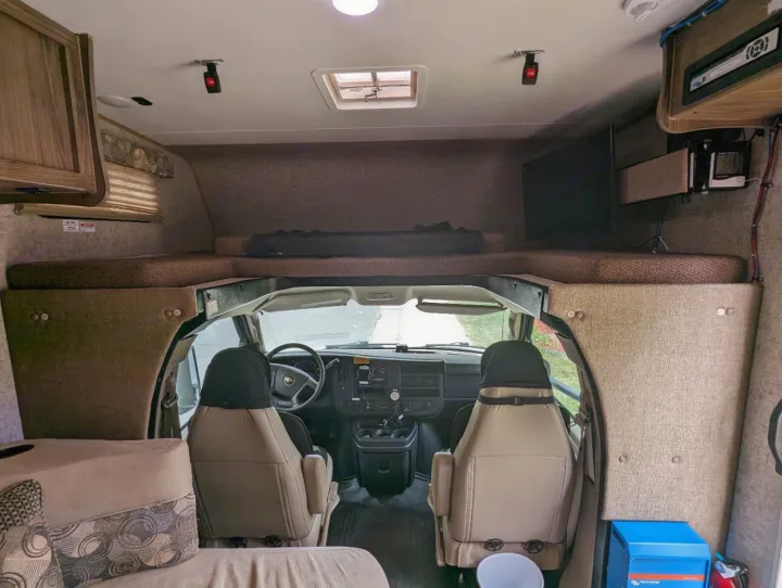 RV rental interior: front cockpit, overhead bunk with mattress, and seating area. Ready for your next adventure.. Forest River Coachmen Freelander 2018