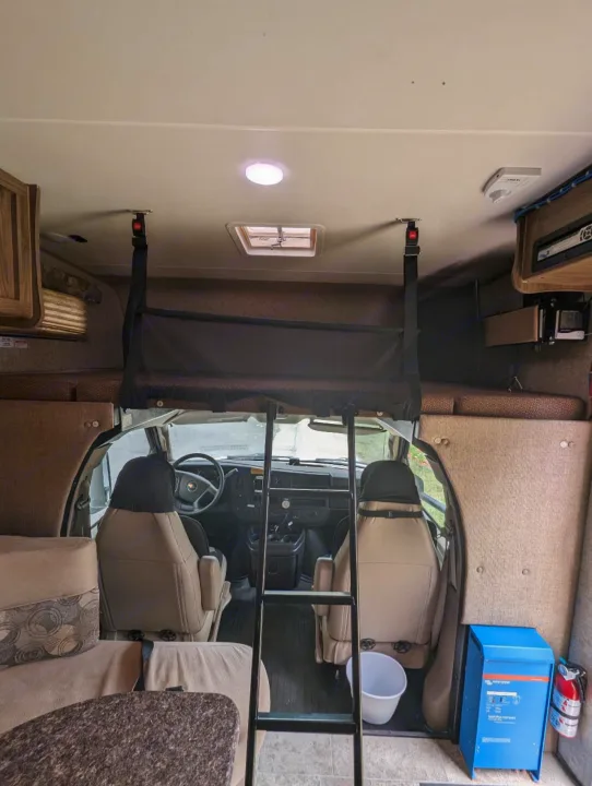 RV rental interior showing the cockpit, over-cab bunk with safety net, ladder, and a power inverter.. Forest River Coachmen Freelander 2018