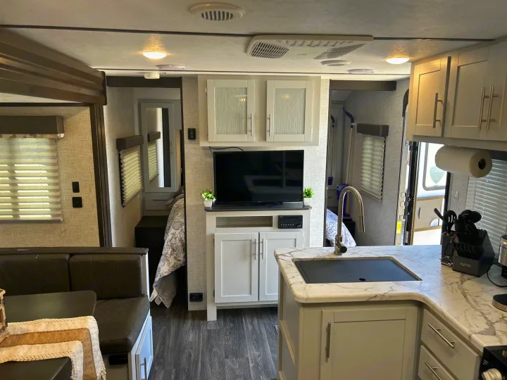 Interior of a modern RV rental, showcasing a well-equipped kitchen, cozy dinette, and entertainment setup. Ideal for travel.. Keystone RV Bullet Ultra Lite 2021