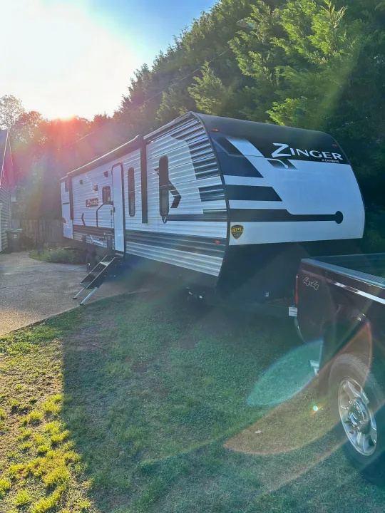 Sunny Zinger travel trailer RV rental, hitched to a truck, ready for your next outdoor adventure.. Crossroads RV Zinger 2022