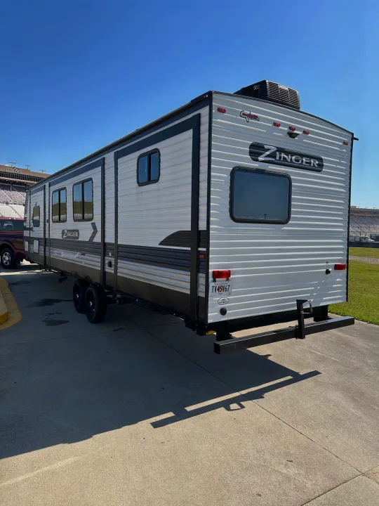 Spacious Zinger travel trailer RV rental parked at a stadium on a sunny day. Ready for adventure!. Crossroads RV Zinger 2022