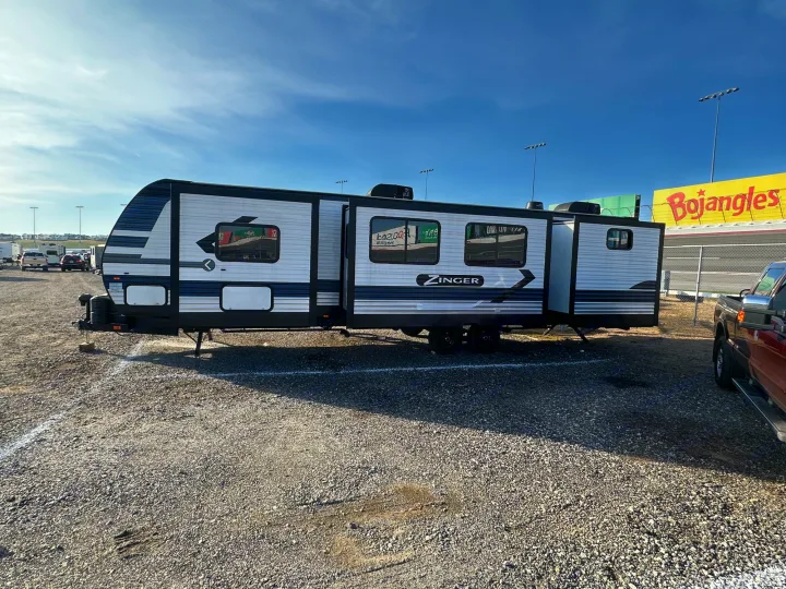 An RV rental (Zinger travel trailer) parked in a sunny gravel lot, slide-outs open, with a Bojangles sign visible.. Crossroads RV Zinger 2022