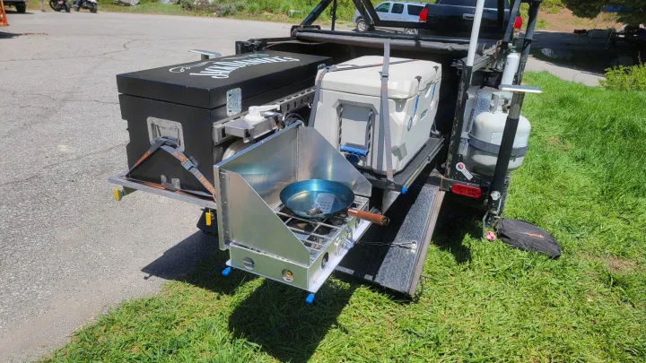 Experience outdoor cooking! This RV rental setup includes a pull-out stove, cooler, & Jack Daniel's storage, ideal for camping.. Insane Custom Trailers "Squatchy" 2022