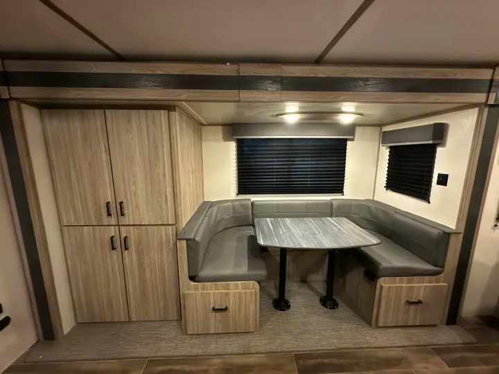 This RV rental features a modern, compact dining area with a U-shaped dinette, perfect for meals & relaxation.. Keystone RV Passport SL 2022