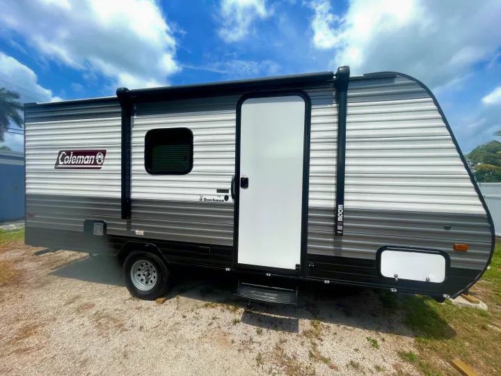 A Coleman Dutchmen Edge travel trailer, ready for RV rental, parked on gravel under a bright, cloudy sky.. Dutchmen Coleman Lantern LT 2023