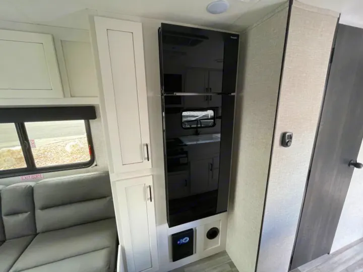 This RV rental features a modern black refrigerator, white storage cabinets, and a comfy gray sofa, ready for your next adventure.. Jayco Jay Flight SLX 2024