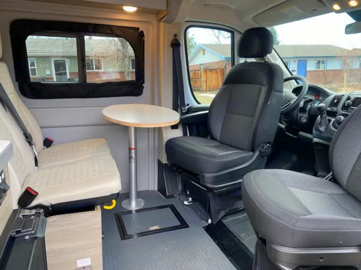 Inside an RV rental: Dinette seating, table, and front swivel seats create a versatile camper van interior.. Winnebago Solis 2021