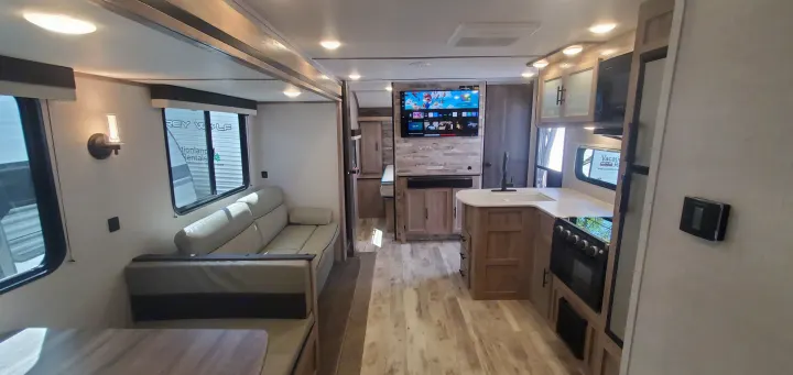 Step into this bright, modern RV rental interior featuring a comfy sofa, dinette, kitchen, and smart TV.. Gulf Stream Trailmaster 2023