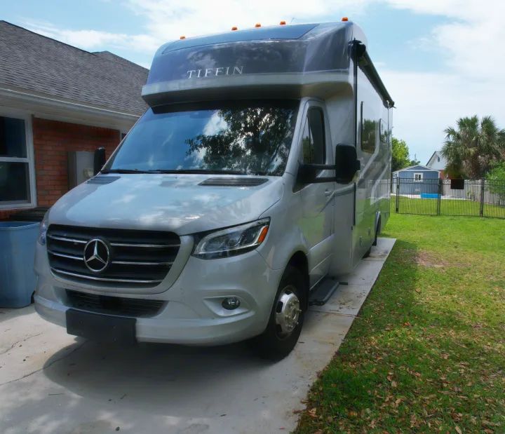 Modern silver Tiffin RV (Mercedes-Benz chassis) parked on a driveway. Consider this comfortable rv rental for your next trip.. Wayfarer Wayfarer Motorhome 2024