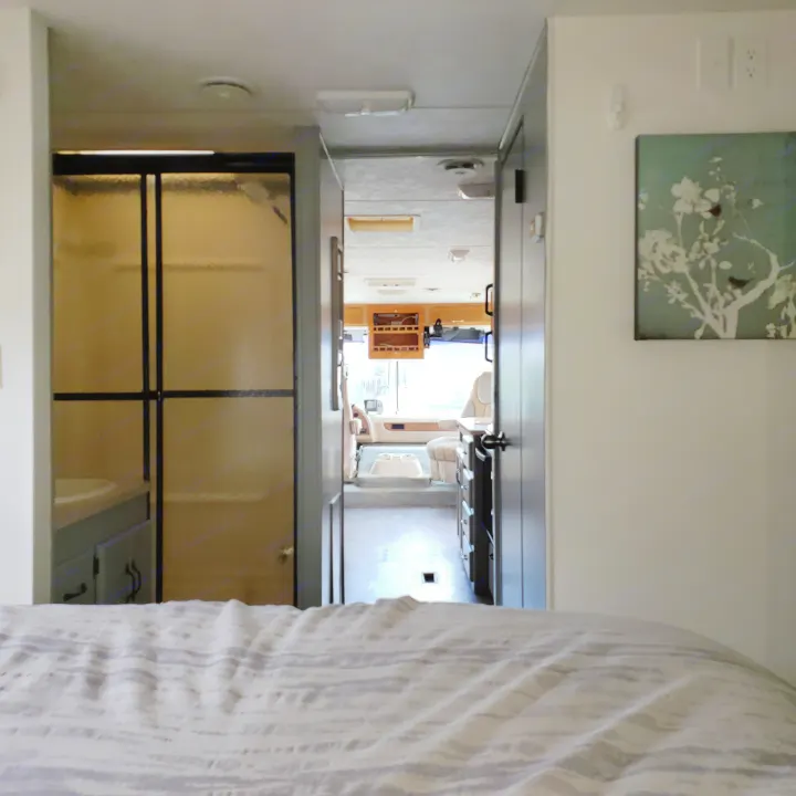 View from the bedroom inside an RV rental, showing the bathroom on the left, hallway, and living area leading to the cockpit.. Damon Corporation Daybreak 2002
