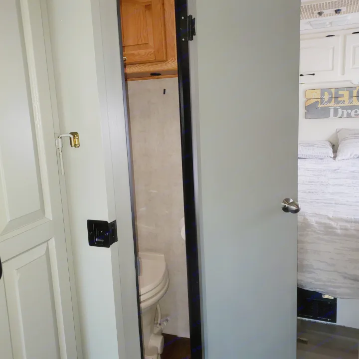 RV rental interior showing a compact bathroom with toilet visible through the door, and an adjacent bedroom.. Damon Corporation Daybreak 2002