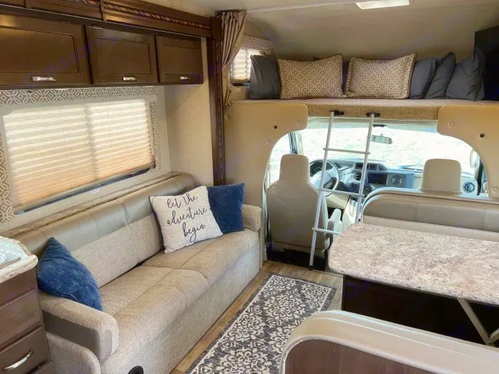 Cozy RV rental interior features a comfy living area with sofa, overhead bunk with ladder, and dinette.. Thor Freedom Elite 2017