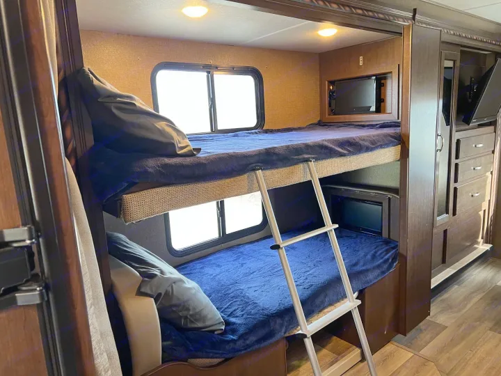 Inside this RV rental: two comfy bunk beds with individual TVs, a ladder, and storage, great for family travel.. Thor Freedom Elite 2017