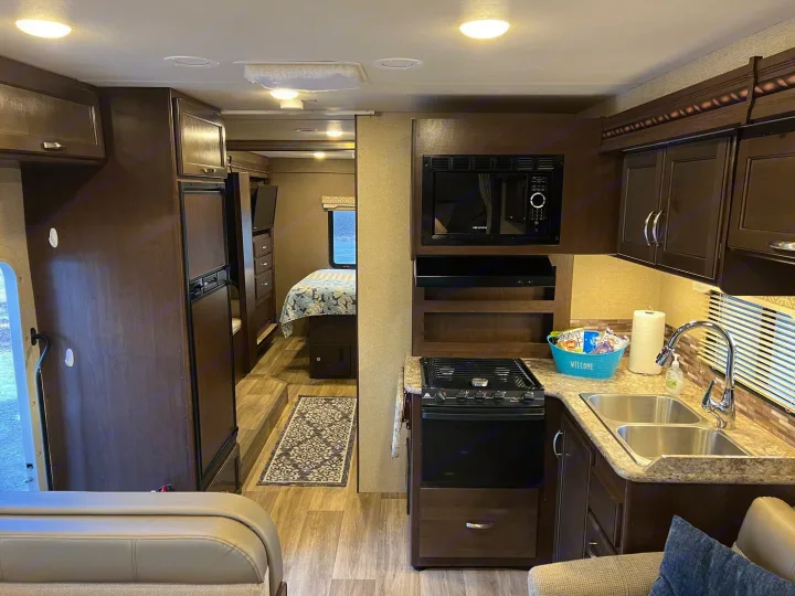 Well-equipped RV rental interior featuring a modern kitchen, comfortable living area, and bedroom.. Thor Freedom Elite 2017