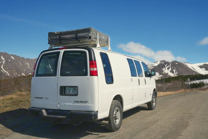 White Chevrolet Express van with a rooftop tent, ideal for an RV rental adventure on scenic mountain roads.. Chevrolet Other 2006