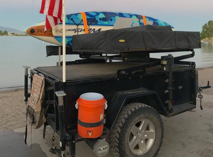 Perfect for your RV rental trip: A utility trailer with rooftop tent, paddleboards, and cooler by the water for outdoor adventures.. Insane Custom Trailers "Squatchy" 2022