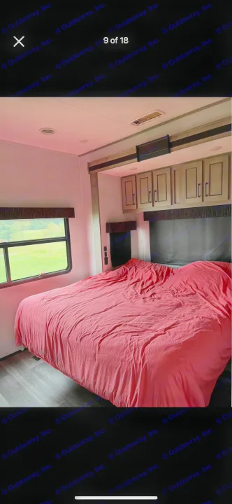 Spacious RV rental bedroom featuring a comfy bed, overhead cabinets, and a picturesque window view.. Heartland RVs Big Country 2021