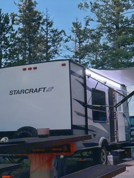 Night view of a Starcraft RV rental at a campsite, with its awning lights on. Perfect for outdoor adventure.. Starcraft Launch Outfitter Extreme 2018