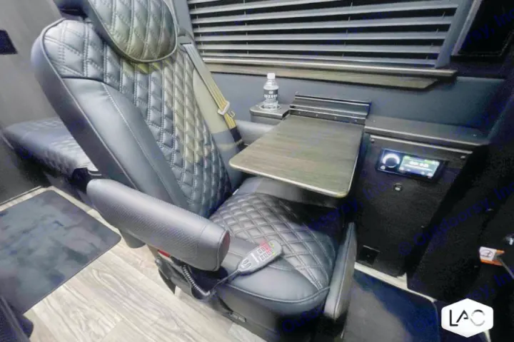 Plush rv rental interior features a black quilted captain's seat with remote, side table, and entertainment.. Midwest Automotive Designs Luxe Cruiser 2024