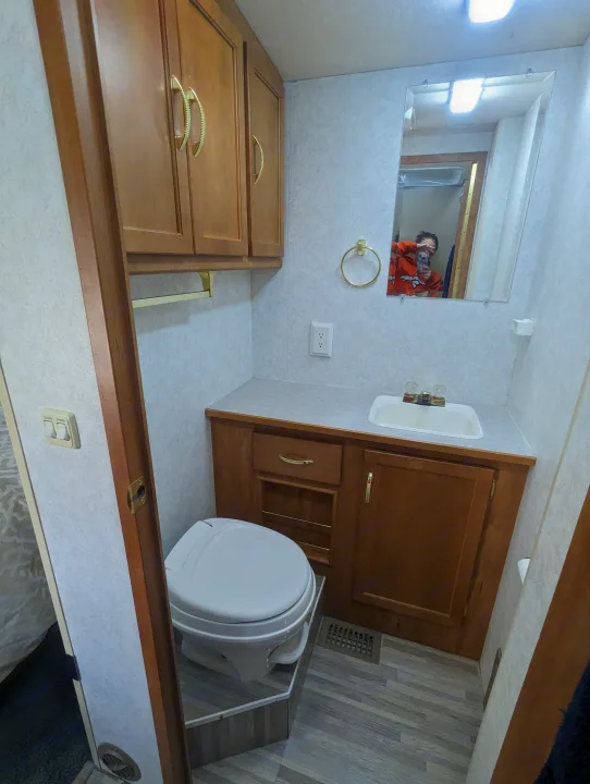Clean RV rental bathroom with toilet, sink vanity, mirror & cabinets. Perfect for your next trip!. Itasca Sunova 2006
