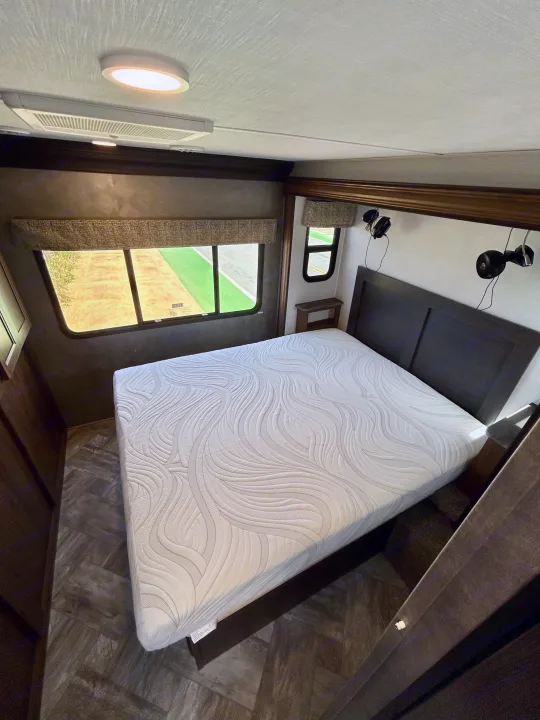 Inside an RV rental: a modern bedroom featuring a comfortable bed, large windows, and sleek flooring.. Forest River Forester 2021