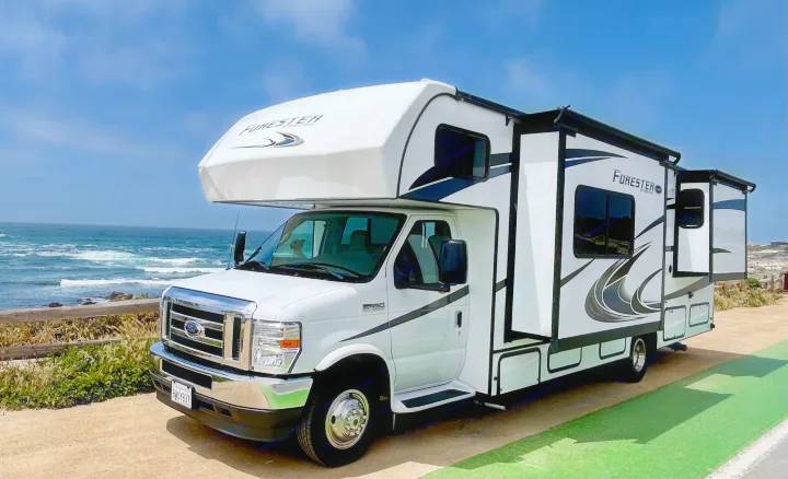Coastal adventure in a white RV rental by the ocean with slide-outs extended. Perfect for your next road trip!. Forest River Forester 2021