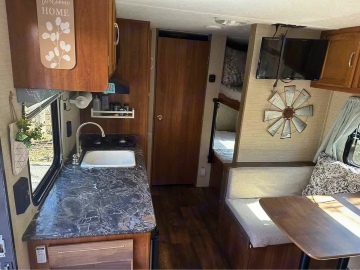 RV rental interior features a bright kitchenette, cozy dinette, bunk beds, and TV for comfortable travel.. Keystone RV Summerland Mini 2017