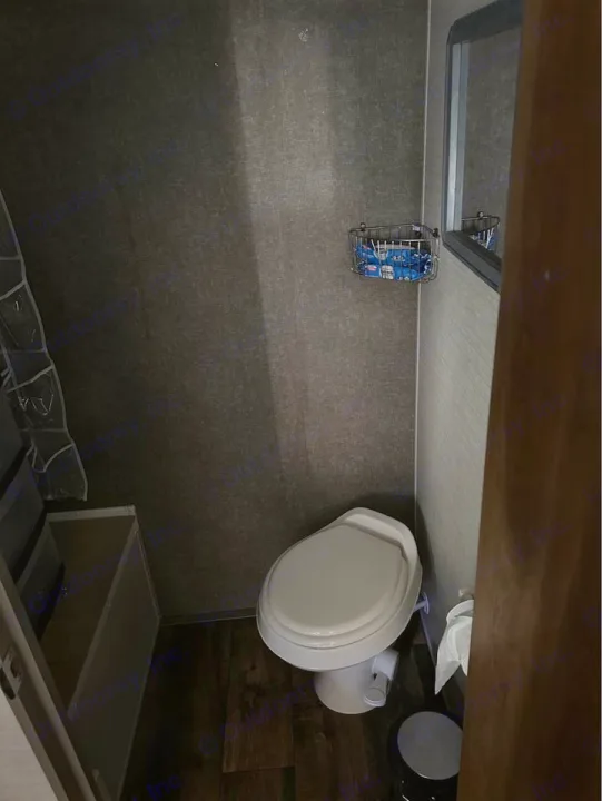 Compact bathroom in an RV rental, featuring a toilet, mirror, and storage. Ideal for travel trailer adventures.. Keystone RV Summerland Mini 2017