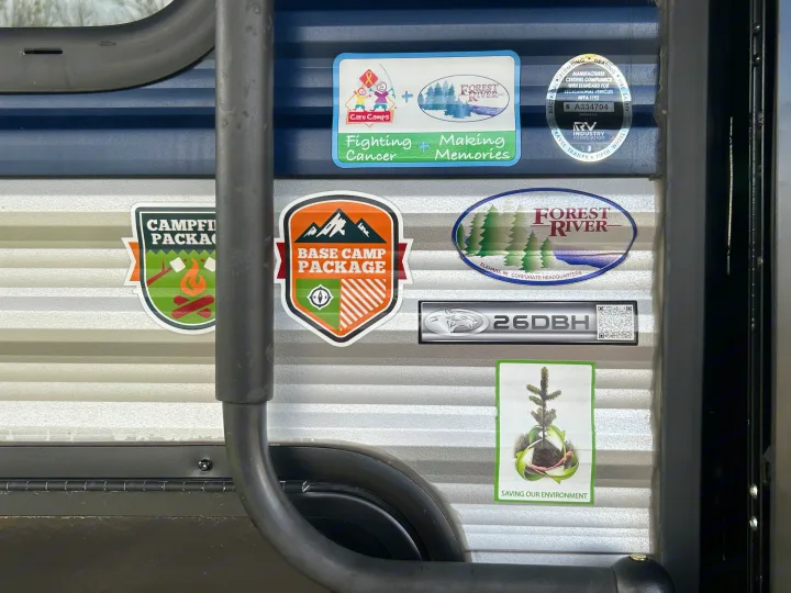 RV rental exterior featuring various package and partnership stickers, including the 26DBH model number.. Forest River Cherokee Grey Wolf 2022