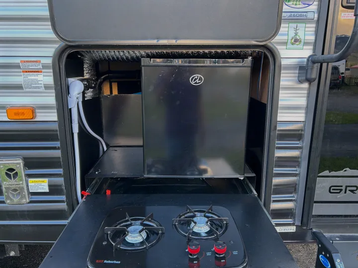 RV rental's outdoor kitchen with a pull-out stove, fridge, and shower connection, perfect for camping.. Forest River Cherokee Grey Wolf 2022
