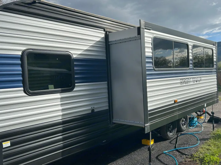 This Grey Wolf rv rental travel trailer with an extended slide-out is set up with hookups in a camping spot.. Forest River Cherokee Grey Wolf 2022