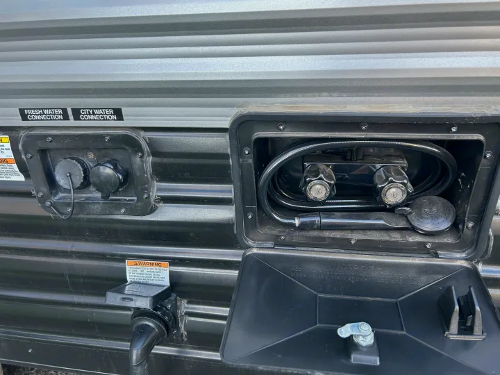 RV rental utility panel: fresh/city water connections, electrical hookup, and an outdoor shower for convenience.. Forest River Cherokee Grey Wolf 2022