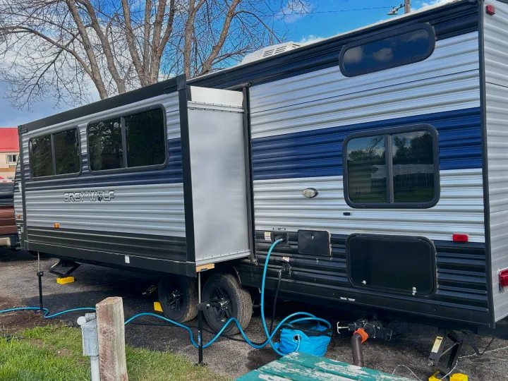 Grey Wolf travel trailer rv rental at a campsite, slide-out extended, hooked up for utilities.. Forest River Cherokee Grey Wolf 2022