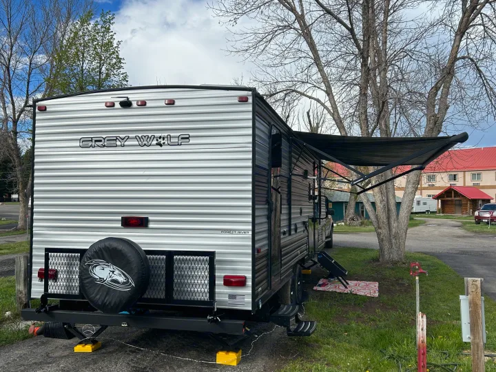 Grey Wolf travel trailer, an rv rental, parked at a campsite. Features extended awning, rear tire mount, and leveling blocks.. Forest River Cherokee Grey Wolf 2022