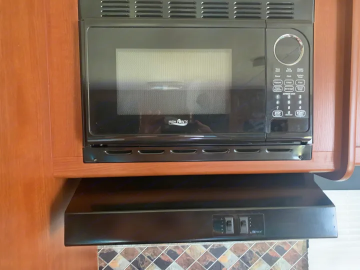 High Pointe microwave and Heng's range hood in a compact **RV rental** kitchen with wood cabinets and a tiled backsplash.. Forest River Salem Cruise Lite 2015