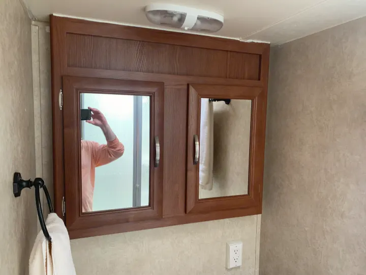 RV rental bathroom interior showing wood medicine cabinet with mirrored doors, ceiling light, and towel ring.. Forest River Salem Cruise Lite 2015
