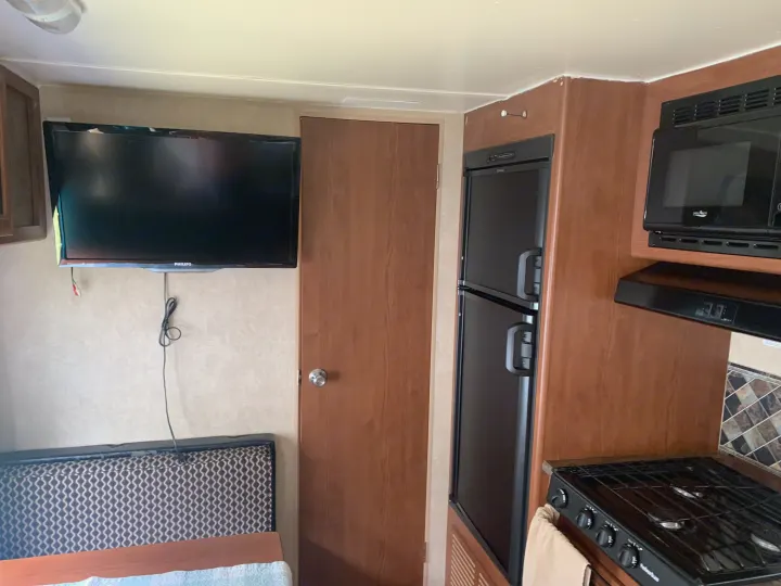 RV rental interior: compact living with a TV, full kitchen featuring microwave, fridge, stove, and a cozy sleeping area.. Forest River Salem Cruise Lite 2015