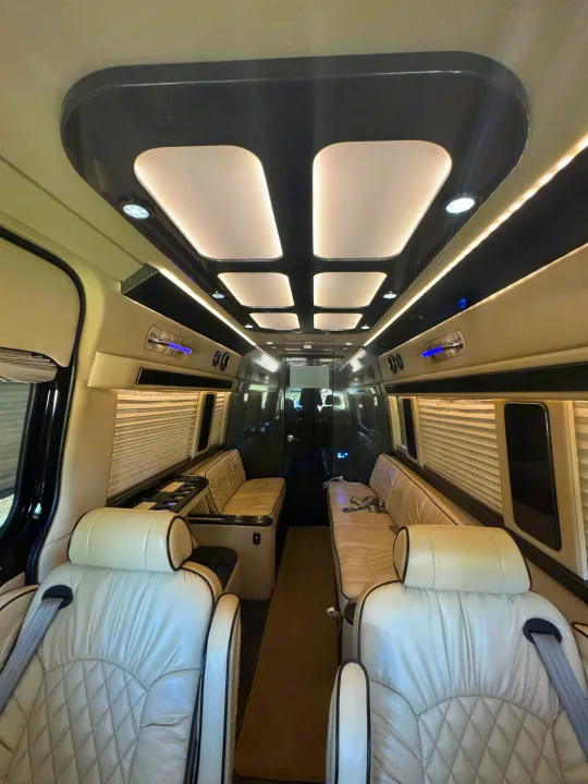 Luxury RV rental: View inside a custom van featuring cream quilted leather seats, ambient lighting, and window blinds.. Midwest Automotive Designs Super Sprinter 2019
