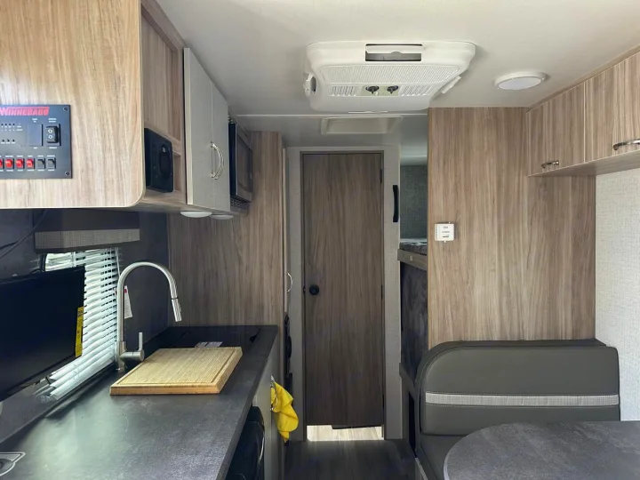The interior of this RV rental features a compact kitchen, dining booth, and bunk beds, offering comfortable travel.. Winnebago Micro Minnie 2022