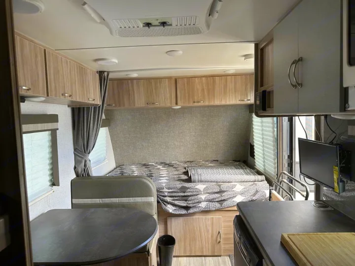 Cozy RV rental interior with a bed, dinette, kitchen counter, and overhead cabinets for comfortable travel.. Winnebago Micro Minnie 2022