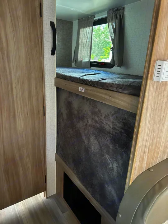 Cozy RV rental interior with bunk beds, showing the top bunk's 250 lbs limit and a window with curtains.. Winnebago Micro Minnie 2022