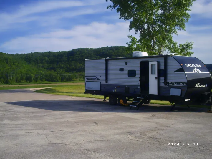 RV rental: Coachmen Catalina travel trailer parked at a scenic site with green hills. Steps down, ready for adventure.. COACHMAN CATALINA 261BHS 2024